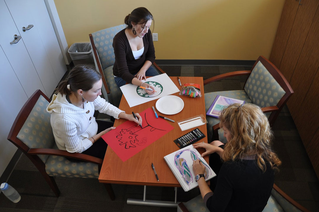 Three people drawing in an art therapy session