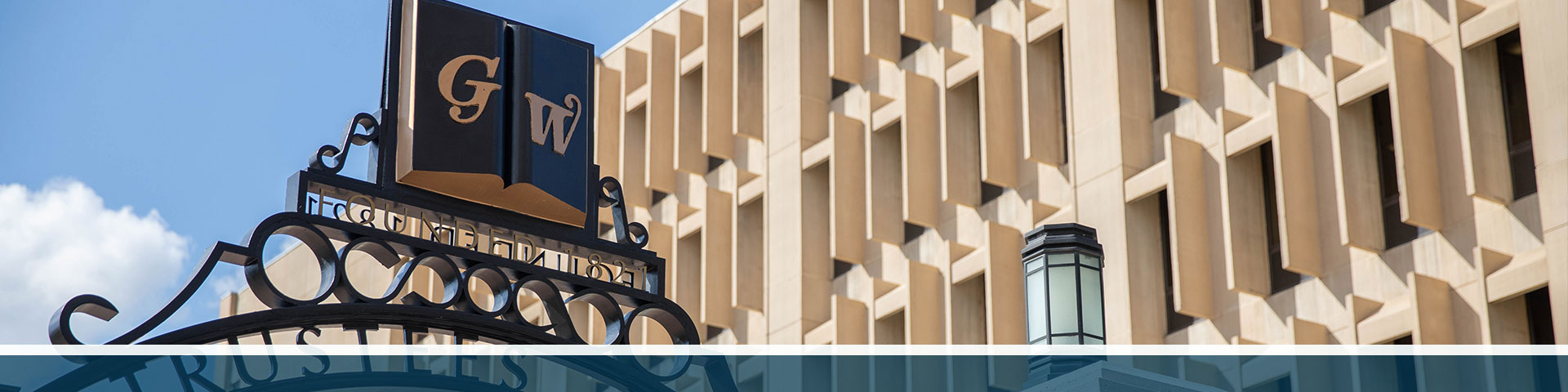 GW Trustees Gate with Gelman Library in the background.