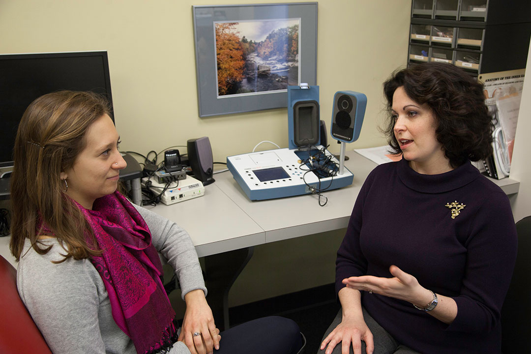 Two people talking to one another in an speech, language and hearing lab